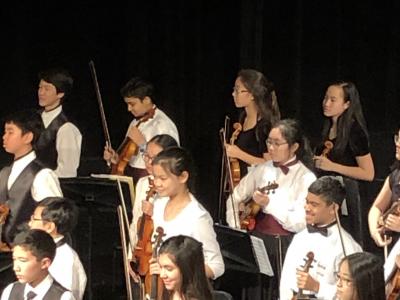 Students standing with strings instruments